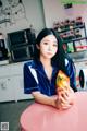 A woman sitting at a pink table holding a bag of chips.