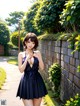 A woman in a blue dress standing next to a stone wall.