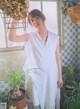 A woman standing in front of a window next to a potted plant.