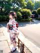 A woman in a kimono standing on a sidewalk.