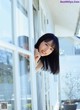 A woman leaning against a window with her hand on the window sill.