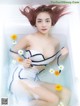 A woman in a bathtub with flowers in her hair.