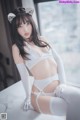 A woman in a white lingerie sitting on a table.