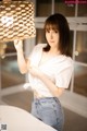 A woman in a white shirt and jeans holding a lamp.