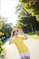 A woman in a yellow shirt and white shorts posing for a picture.