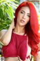 A woman with long red hair wearing a red bra.