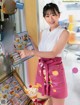 A woman in a pink apron holding a menu.